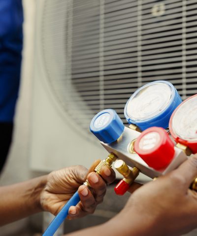 Close up of competent mechanic holding manometers used for checking hvac system refrigerant. Expert repairman using manifold indicators to check high or low freon levels of air conditioner tank
